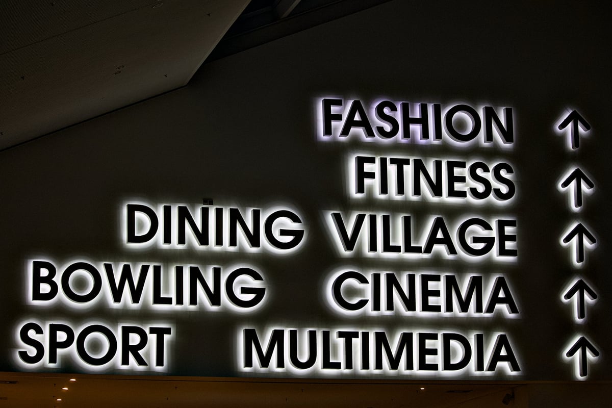 Illuminated directional sign with backlit letters in a commercial building